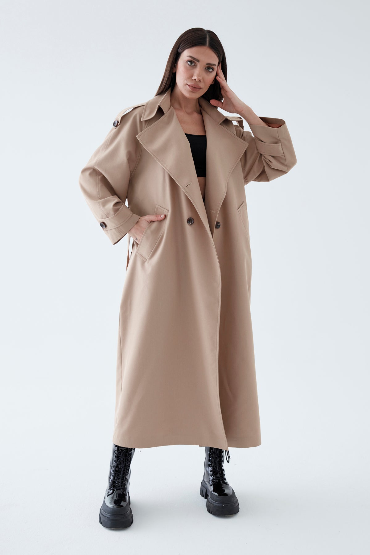 Woman wearing a beige trench coat on a white background
