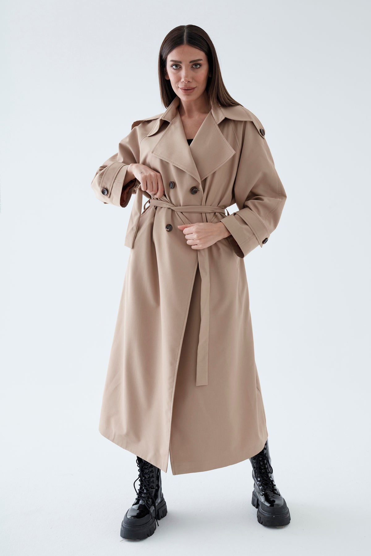 Woman wearing a beige trench coat on a white background