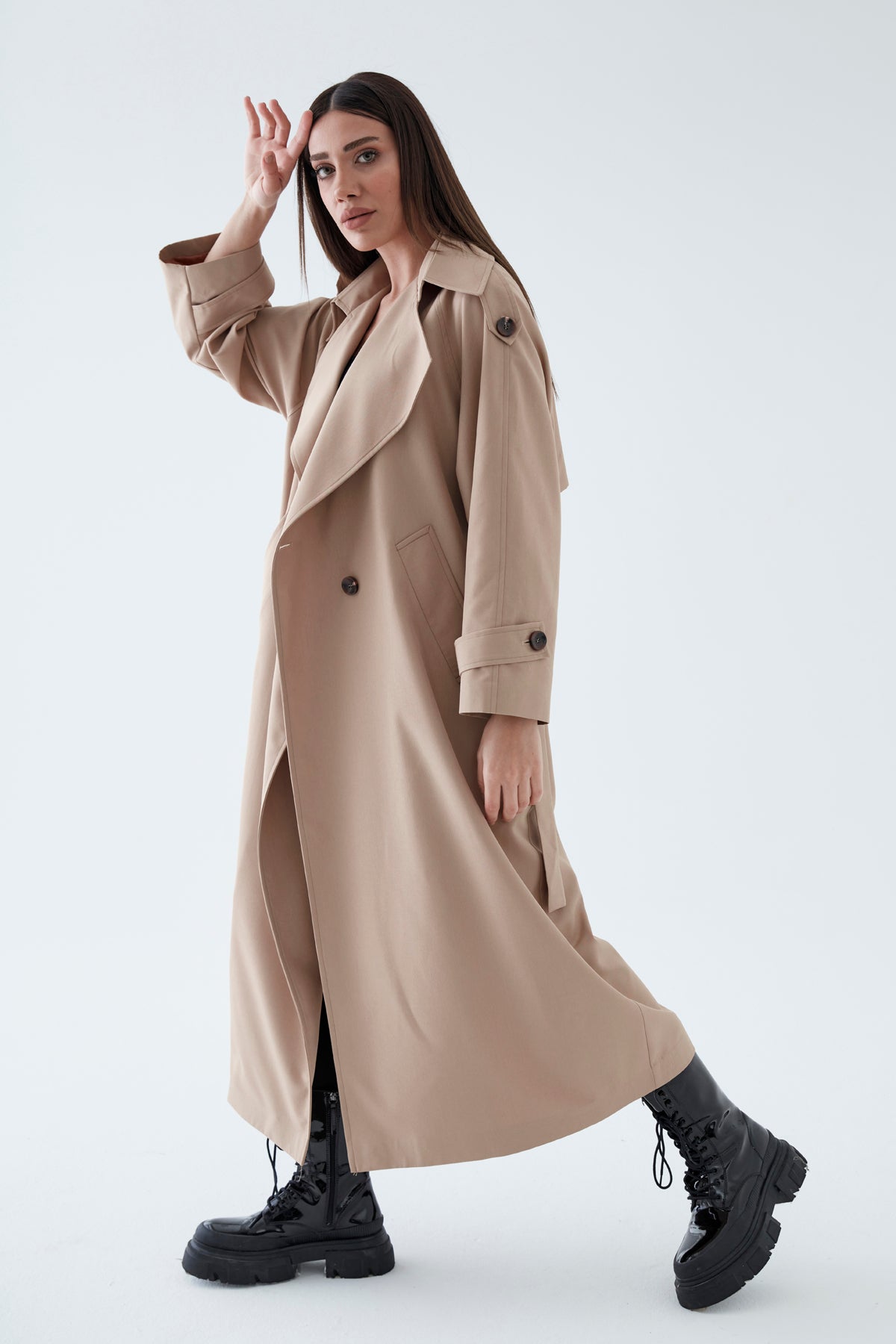 Woman wearing a long beige coat on a white background