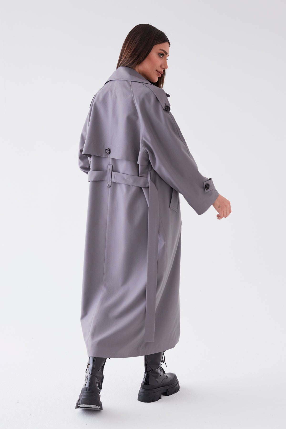 Woman wearing a long gray coat on a white background