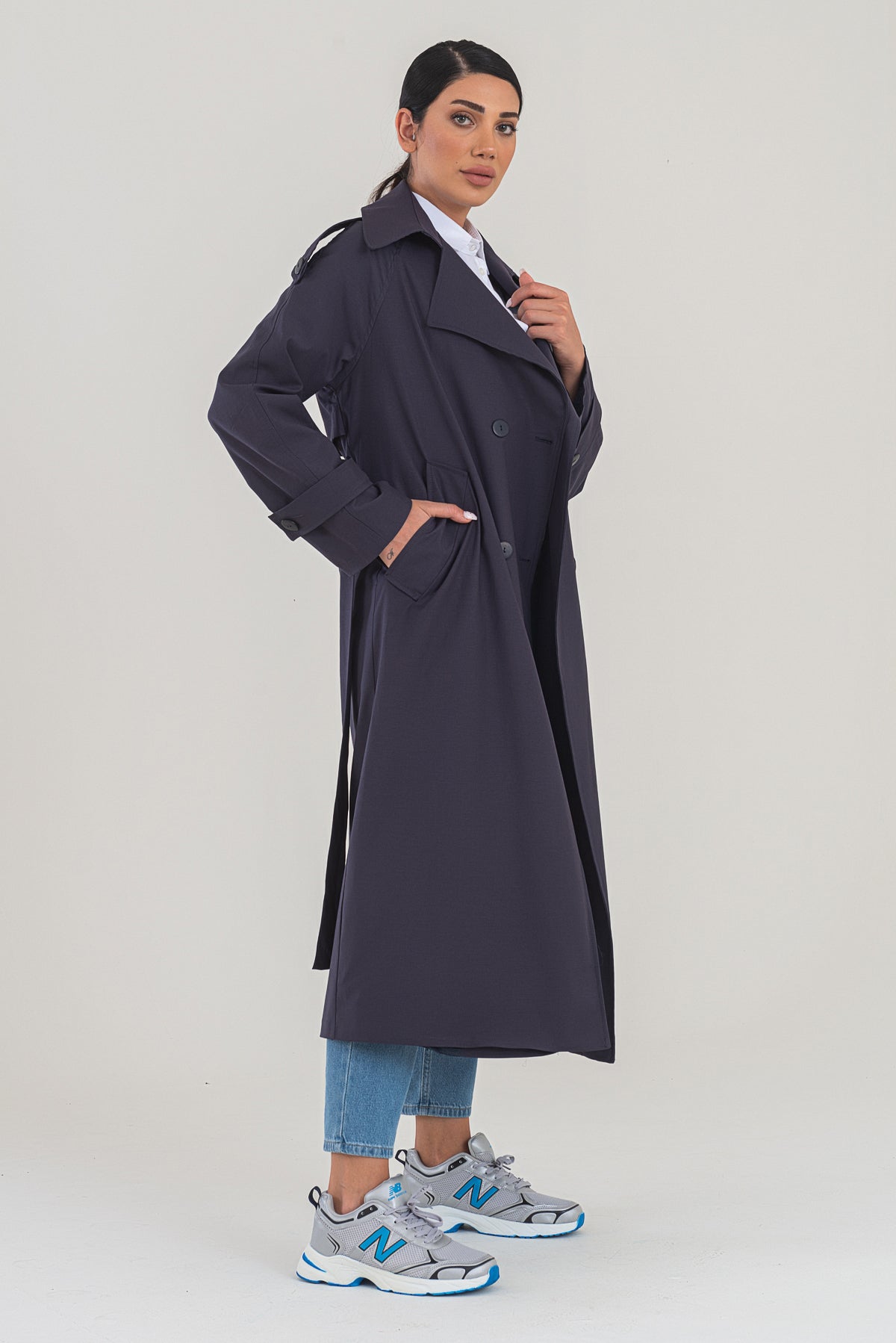 Woman wearing a long dark coat on a white background