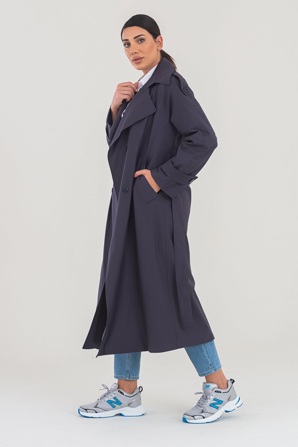 Woman wearing a long dark coat on a white background