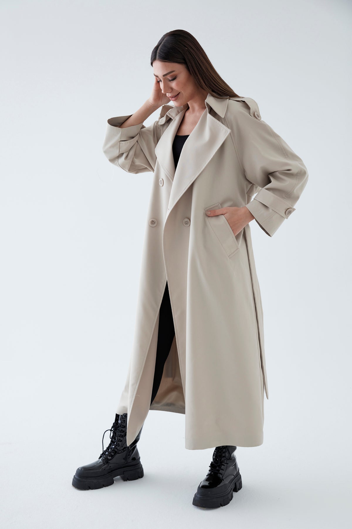 Woman wearing a beige trench coat on a white background