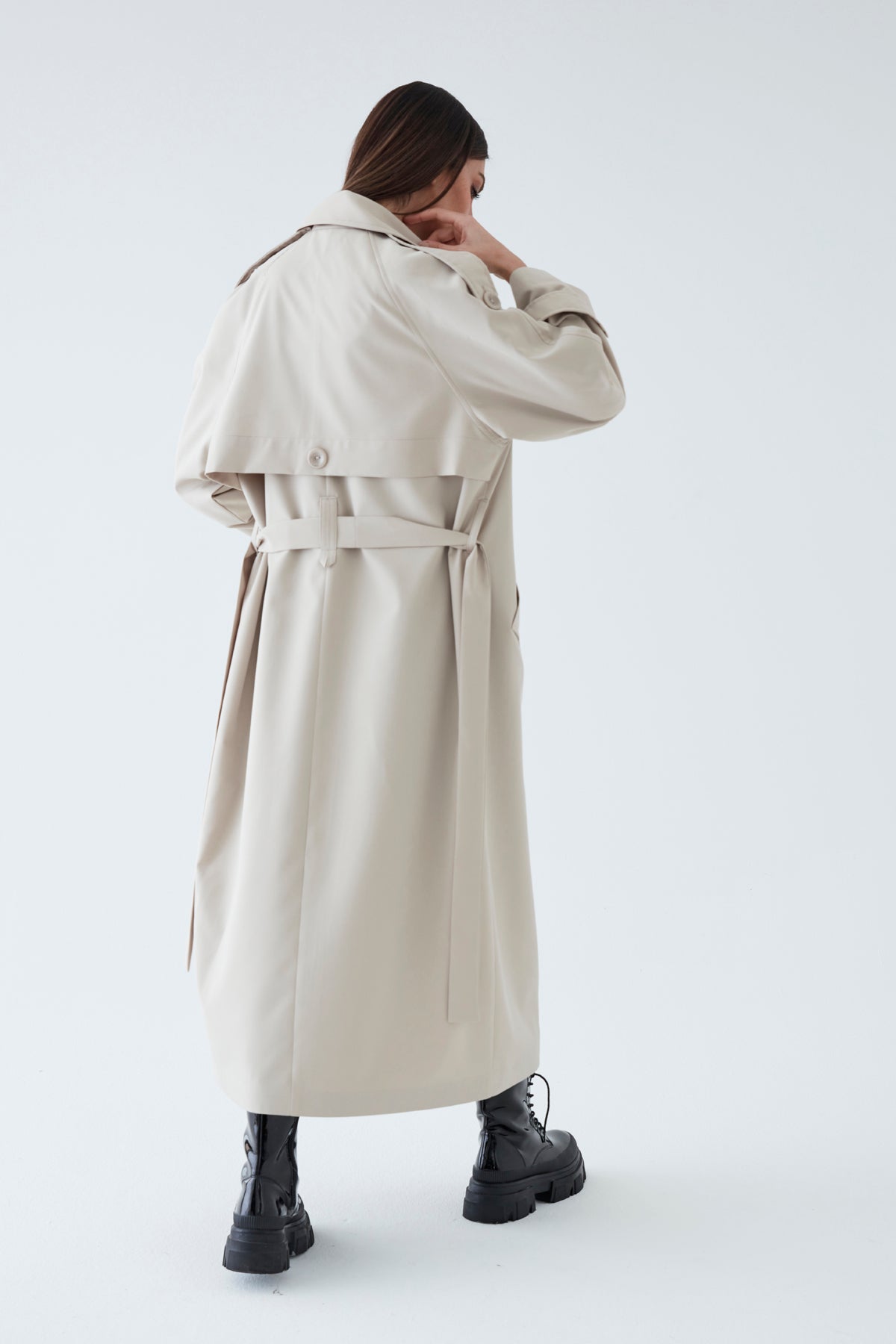 Person wearing a long beige coat on a white background