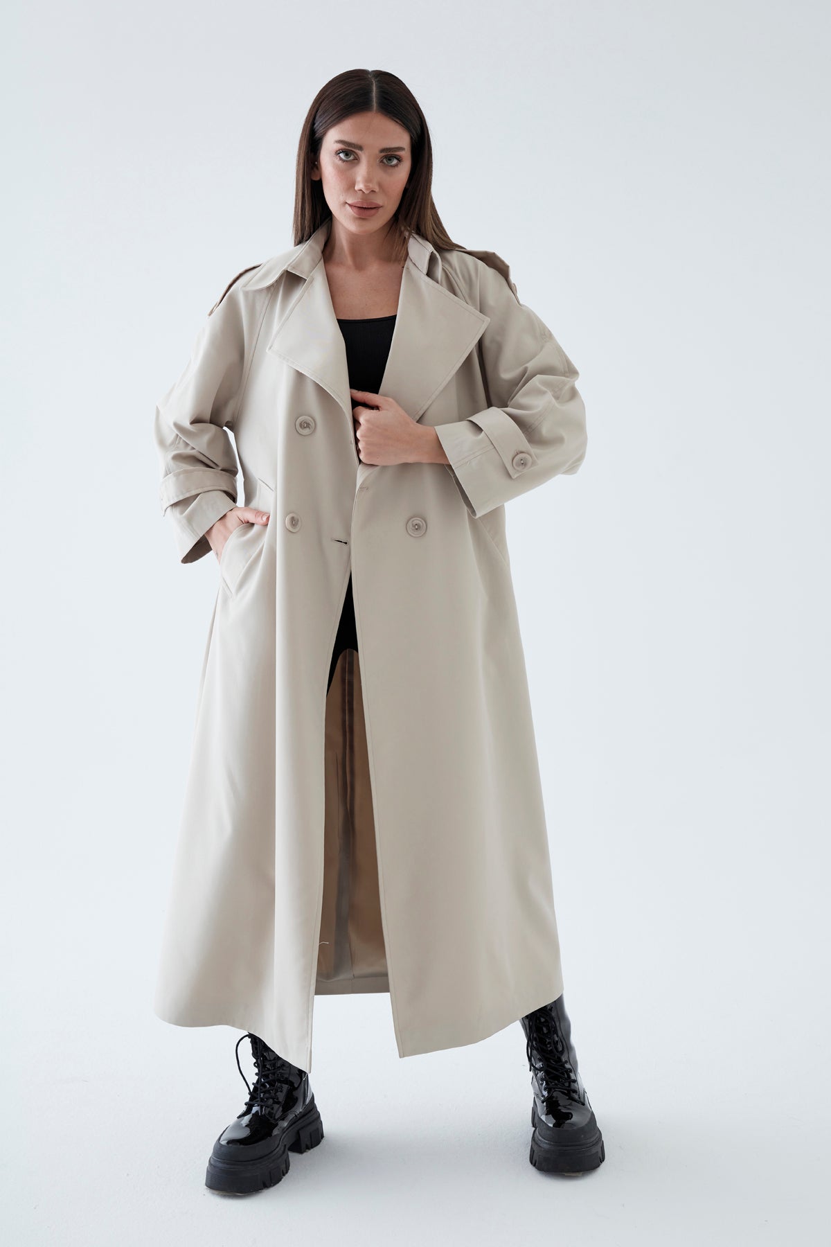 Woman wearing a long beige coat on a white background